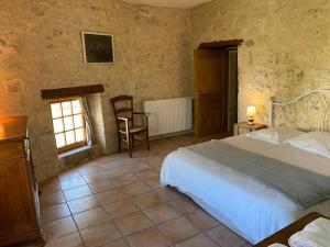 DondasGîte La Maison du Bonheur的卧室配有1张床、1张桌子和1把椅子
