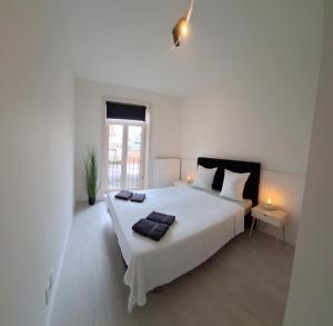 梅赫伦Huis ALNA 3的白色的卧室设有一张白色大床和一个窗户。