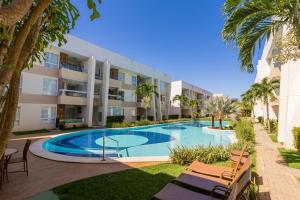 瓜拉久巴Apartment in Guarajuba with 2 Comfortable Suites.的棕榈树建筑前的游泳池