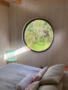 瓦尔迪维亚Riberas del Futa的一间卧室设有圆形窗户和一张带枕头的床