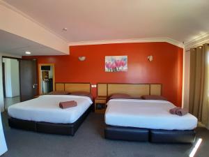 玻璃市港口THE ZULEY HERITAGE HOTEL的橙色墙壁的客房内的两张床