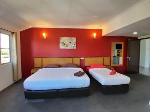 玻璃市港口THE ZULEY HERITAGE HOTEL的红色墙壁的客房内的两张床