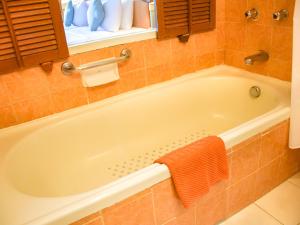 南芭堤雅Asia Pattaya Hotel的带浴缸的浴室,配有橙色毛巾