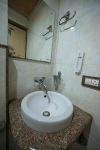 西里古里Rajdarbar Hotel & Banquet, Siliguri的浴室设有白色水槽和镜子