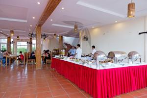 Hưng LongTre Nguồn Thiên Cầm Hotel&Resort的一间有红色桌子的餐厅,有准备食物的人