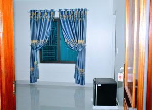 荣市Vinh Airport Hotel的房间里的窗户上有两块蓝色窗帘