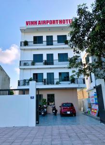 荣市Vinh Airport Hotel的一间白色的酒店,前面有一辆汽车