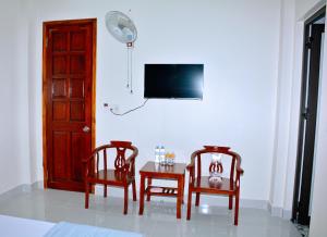 荣市Vinh Airport Hotel的一间设有两把椅子、一张桌子和一台电视的房间