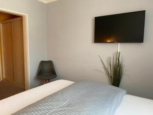 巴特萨尔茨乌夫伦Weinhotel Römerbad的卧室配有一张壁挂式平面电视的床。