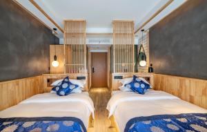 张家界Cozy Boutique Hotel的客房配有两张带蓝白色枕头的床。