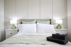 诺里奇Elegant Design 75" Smart Tv Long Stay Welcome的配有白色枕头和两盏灯的白色床