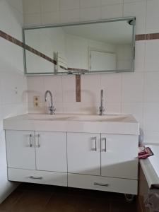 WaardeB&B Waardevol, Julianastraat 2L的白色的浴室设有两个盥洗盆和镜子