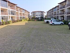 乌旺戈海滩24 Topanga的公寓大楼前设有停车场,可停放汽车。
