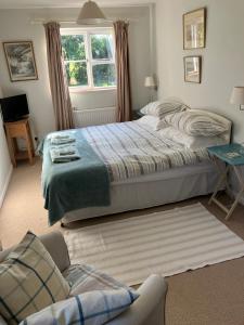 伍德布里奇Snipe Vineyard Cottage的一间卧室配有一张床、一张沙发和一个窗口