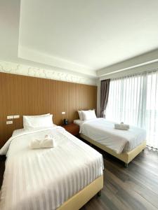 清迈Baannalin Hometel บ้านนลิน โฮมเทล的酒店客房设有两张床和窗户。