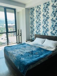巴库里阿尼BOBLINE BAKURIANI SUITE的一间卧室配有一张带蓝色毯子的床和窗户。