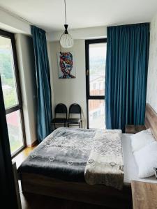 巴库里阿尼BOBLINE BAKURIANI SUITE的一间卧室配有一张带蓝色窗帘的大床
