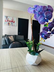 巴库里阿尼BOBLINE BAKURIANI SUITE的花瓶,花朵紫色,坐在桌子上