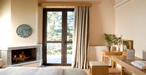 维蒂纳Natura Hotel Vytina的一间卧室设有壁炉、一张床和一个窗户。