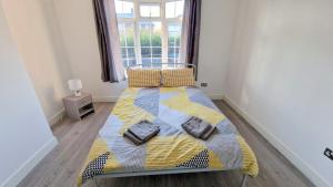米查姆Lilleshall Rooms的一间卧室配有一张黄色和蓝色毯子的床