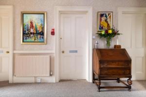 林顿Highcliffe House的一间设有门、桌子和绘画的房间