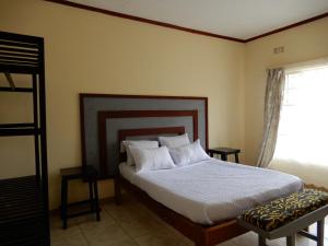 利隆圭Quest的一间卧室配有一张带白色床单的床和一扇窗户。