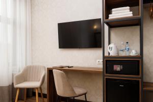 利沃夫Feder Boutique Hotel的客房设有一张桌子、一台电视和椅子