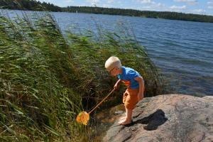 Sankt AnnaSankt Anna Resort的湖边的岩石上用网子玩的男孩