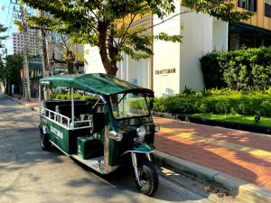 曼谷曼谷工匠酒店的停在街道边的一辆绿色小汽车