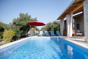 伦Island Villa Adriana with heated pool and sauna的一个带红色遮阳伞和桌椅的游泳池
