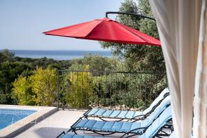 伦Island Villa Adriana with heated pool and sauna的游泳池畔的两把椅子和一把红伞