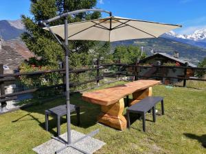 格雷桑Maison Cenne Vda Gressan n 0030的木桌和带雨伞的长凳