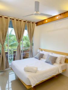 KendhooDhoani Maldives Guesthouse的卧室在窗户前配有一张白色大床