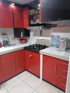 齐克拉约Residencial Las Torres de Salaverry的厨房配有红色橱柜和炉灶烤箱