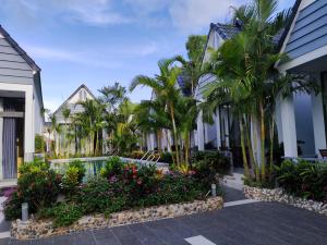 富国Ngoc Trai Xanh Bungalow的棕榈树和鲜花的房子的庭院
