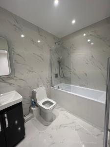 伦敦Lovely 1-bedroom flat with Patio的浴室配有卫生间、浴缸和水槽。