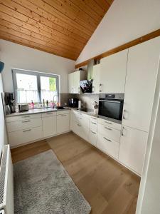 维赫尔Wiehler- Ferienwohnung的厨房配有白色橱柜和木制天花板