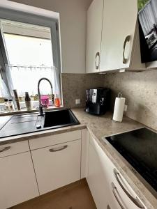 维赫尔Wiehler- Ferienwohnung的厨房配有白色橱柜、水槽和窗户。