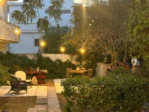 斯巴达Paola’s apartments near Athens Airport的花园在晚上设有长凳和桌子