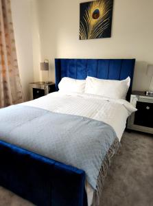 谢菲尔德Spacious detached 3 bed,2 bath house with private garden&parking located near city centre的卧室内的一张带蓝色床头板的大床