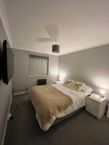 南安普敦Newly Refurbished Apartment with private parking的一间卧室配有一张带两盏灯的床和一台电视。