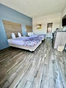 克利本Delux Inn Cleburne的一间卧室设有两张床,铺有木地板