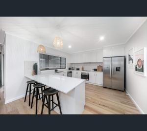 沃加沃加Brand New Luxury Abode on Shaw的白色的厨房,配有柜台和凳子
