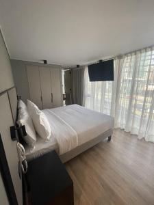 圣地亚哥One Manquehue Aparthotel的卧室配有一张带白色床单和窗户的大床。