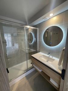 圣地亚哥One Manquehue Aparthotel的带淋浴、盥洗盆和镜子的浴室