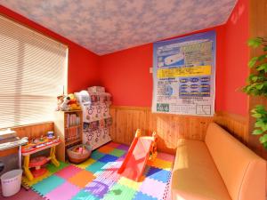 武雄市北方温泉四季の里　七彩の湯的一间设有红色墙壁和游乐区的儿童房