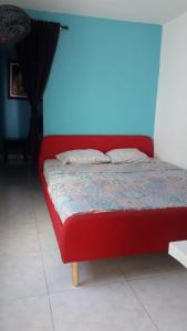圣玛尔塔Casa Amplia Completa Privada para Familias的蓝色墙壁的房间里一张红色的床