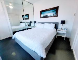 Henley Beach SouthZig Zag at Henley ~ BEACH ~ DINING ~ WiFi ~Airport的卧室配有一张白色大床和镜子