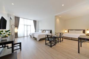曼谷Oldthaiheng Hotel的酒店客房带两张床和一张桌子以及椅子。