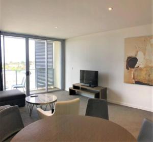 悉尼Serain Residences on 88 Archer Chatswood的客厅配有电视和桌椅